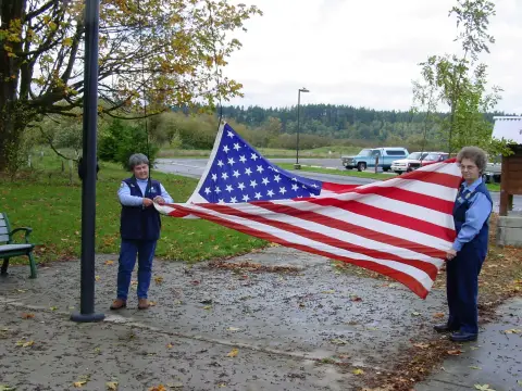 Les volontaires du refuge Karen Yochem, à droite, et Barb Sullivan, à gauche, se préparent à lever le drapeau au Billy Frank Jr. Nisqually National Wildlife Refuge à Washington. 