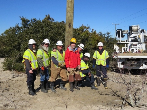 Reese Lukei, volontaire du refuge, dans la veste rouge, pose avec un équipage de Dominion Virginia Power après avoir installé une plate-forme de balbuzard pêcheur au Back Bay National Wildlife Refuge en Virginie.