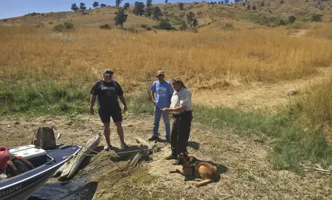 trois personnes debout dans un champ avec un chien au sol