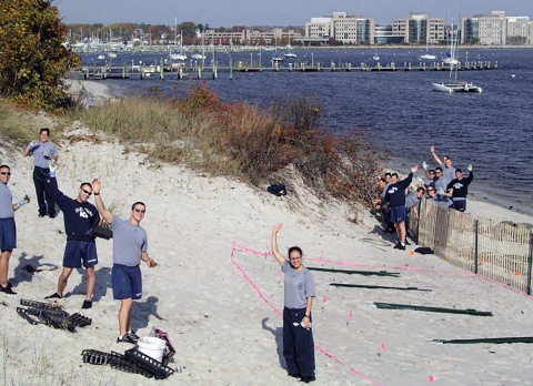 Des bénévoles de l'US Coast Guard Academy debout et agitant sur des dunes de sable à New London, CT