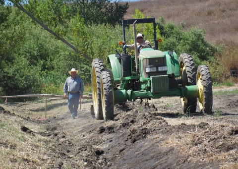 Un homme marchant à côté d'un gros tracteur vert