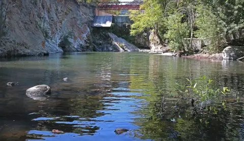 Photo de paysage d'une rivière avec des rochers et un barrage en arrière-plan.