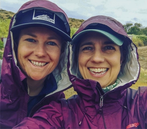 Deux femmes souriantes et portant des imperméables violets