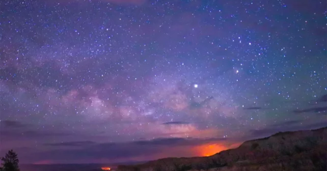Image d'un ciel indigo et rose avec des étoiles visibles.