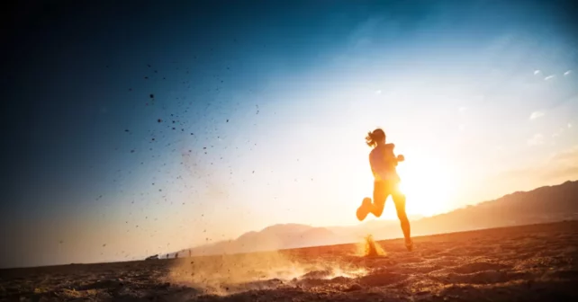 Un coureur se découpant sur un paysage désertique au coucher ou au lever du soleil.