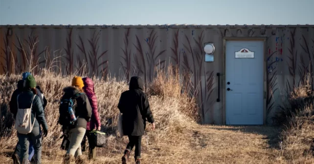 Le dos de plusieurs personnes portant des vêtements pour temps froid alors qu’elles se dirigent vers la porte d’un store.