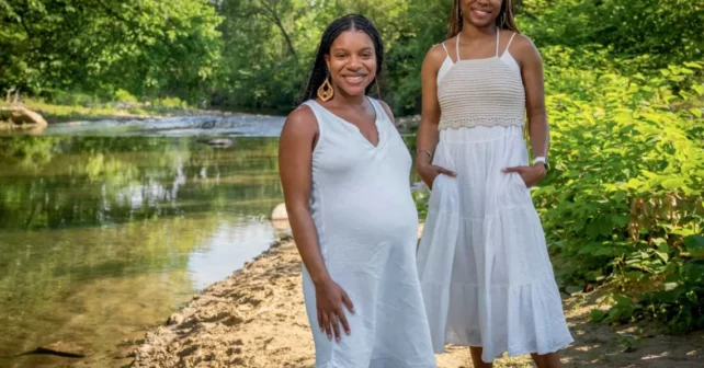 Diamon Clark et Kristen Walker se tiennent près d'une crique bordée d'arbres, vêtues de longues robes blanches.