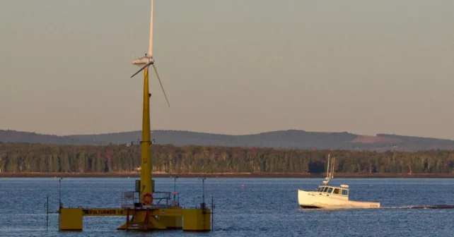 Une éolienne offshore flotte au large des côtes du Maine avec un homardier et une forêt en arrière-plan