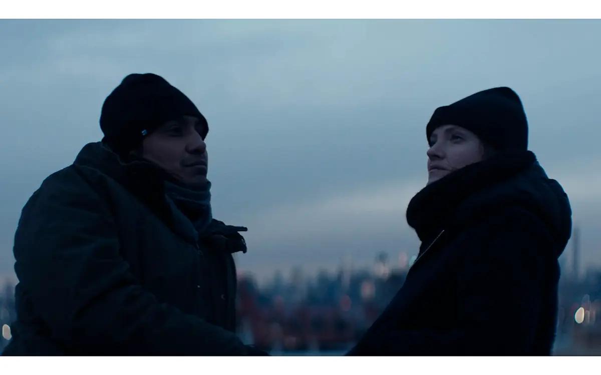 Deux personnages emmitouflés dans des vêtements d'hiver sur un toit, se découpant sur le ciel.