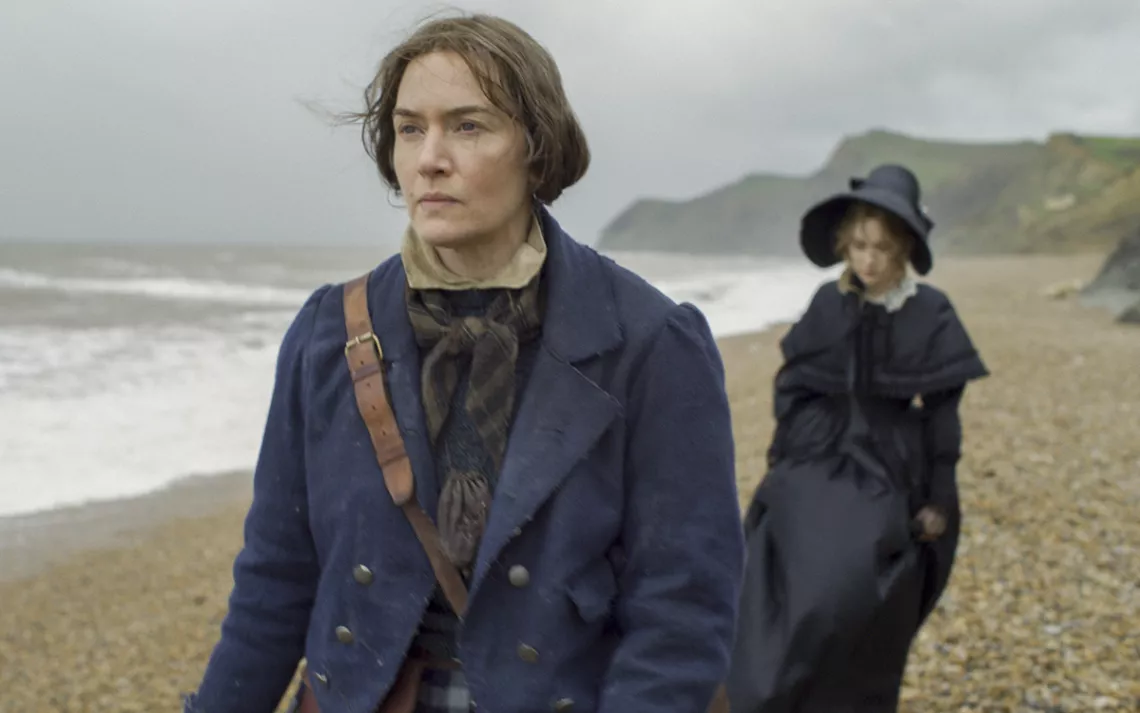 Kate Winselt et Saoirse Ronan marchent le long d'une plage venteuse, portant des bonnets à l'air sombre