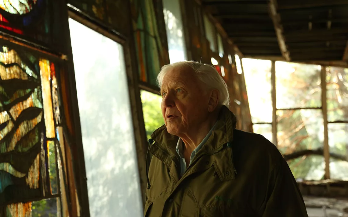 Sir David Attenborough photographié à l'intérieur d'un bâtiment abandonné à Tchernobyl, en Ukraine.