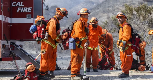 Pompiers en combinaison orange de lutte contre les incendies devant.  d'un paysage brumeux de Californie