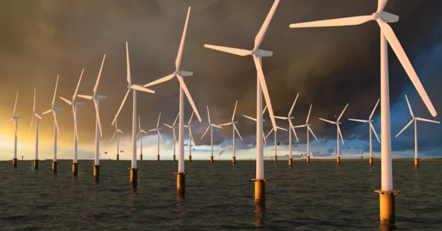 Rangée d'éoliennes debout dans un océan sombre, contre un ciel maussade contre un soleil couchant.