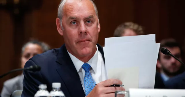 Le secrétaire de l'Intérieur Ryan Zinke tient des papiers lors d'une audience.