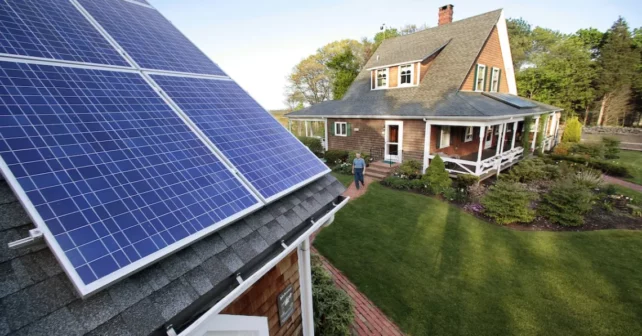Len Bicknell se promène de sa maison à son garage où ses panneaux d'énergie solaire sont montés sur le toit à Marshfield, dans le Mass.
