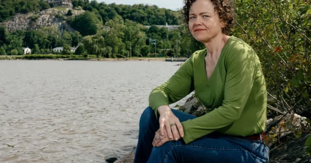 Courtney Williams porte une chemise verte et assise à côté d'une rivière.