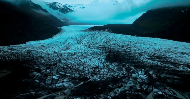 Un ciel sombre et de la brume apparaissent au-dessus de la montagne et de la glace du glacier Svínafellsjökull en Islande.