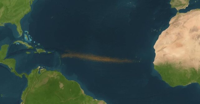 Mapa satelital del océano Atlántico con un cinturón de polvo sahariano en suspensión extendiéndose desde África hacia el Caribe.