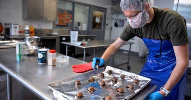 Investigador de Cornell preparando albóndigas con 20% de orujo de manzana en laboratorio alimentario.
