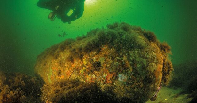 Bomba química de la Segunda Guerra Mundial oxidándose en el fondo del mar Báltico junto a un buzo investigador.