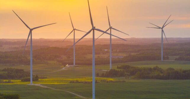 Aerogeneradores gigantes en un parque eólico de Lituania produciendo energía renovable al atardecer.