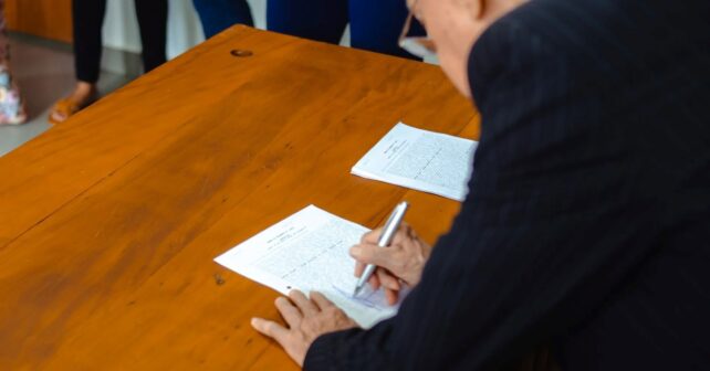 Persona firmando el testamento solidario para proteger la naturaleza junto a iniciativas de conservación ambiental